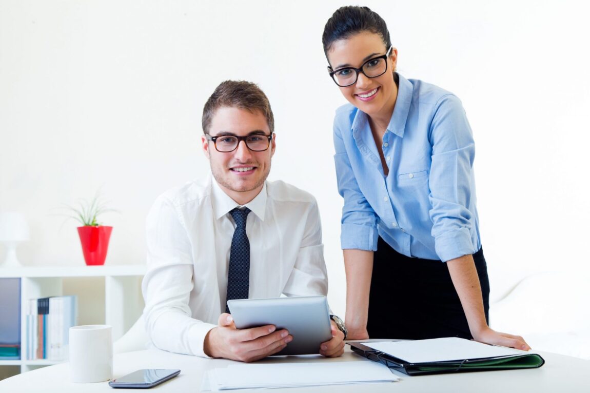 Photo of man and woman smiling in office illustrates blog: "Taking a Few Days Off? Use This Checklist"