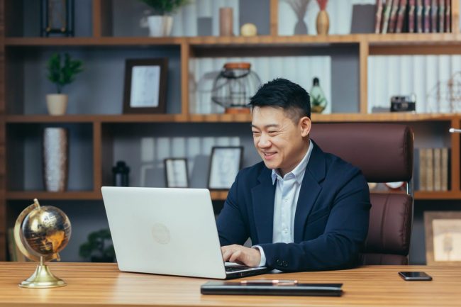 Photo of businessman looking at laptop illustrates blog: "How to Find a Mentor When You Work Remotely"