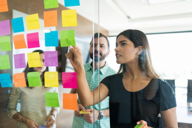 Photo of team collaborating with sticky notes in front of them illustrates blog: "Beware of Collaborative Overload"