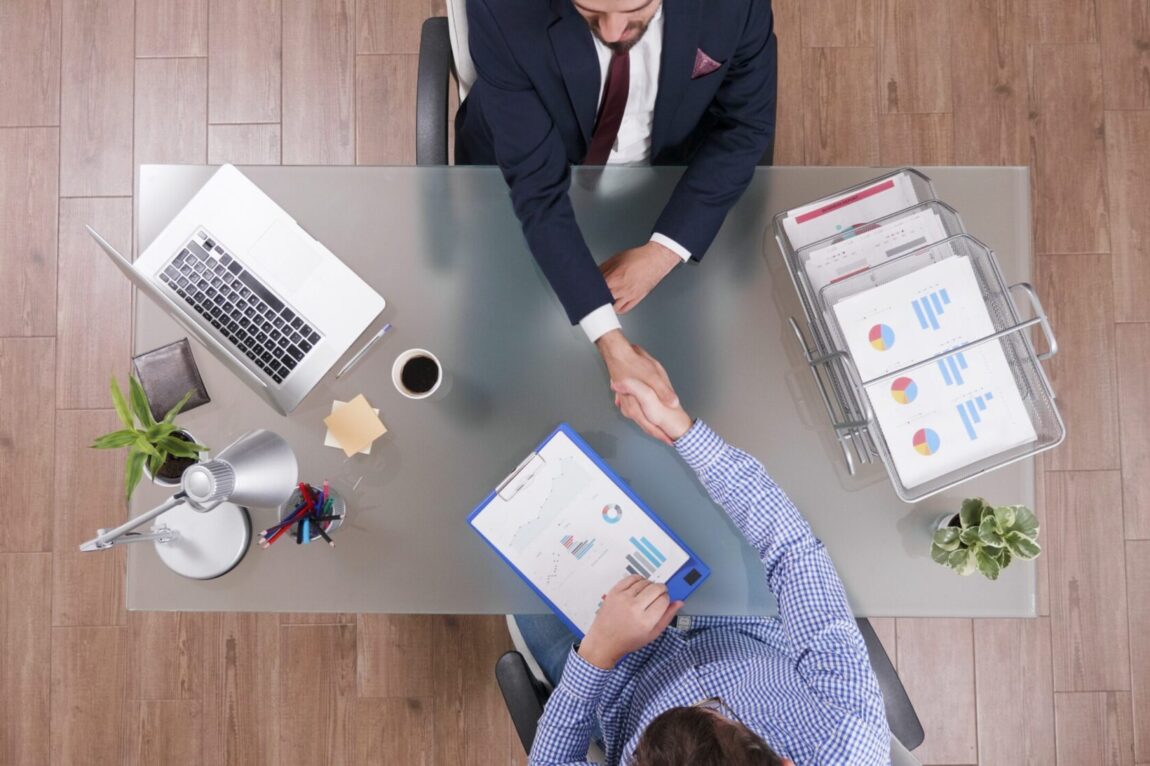 Aerial view of two men shaking hands illustraes blog "4 Questions To Ask Yourself Before Taking Out a Business Loan"