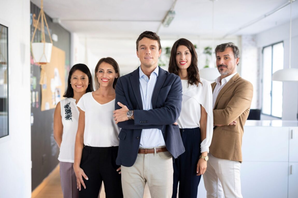 Photo of people standing in office illustrates blog: "How To Stand Out as an Employer (And Why You Should Care)"