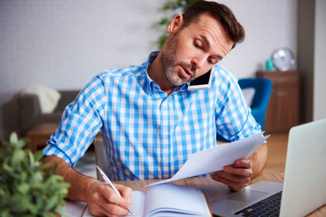 Photo of man talking on the phone and writing illlustrates blog "Here's Why You Shouldn't Multitask"