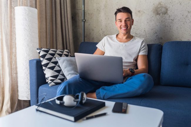 Photo of smiling man in sofa with laptop illustrates blog: "The Importance of Microbreaks"