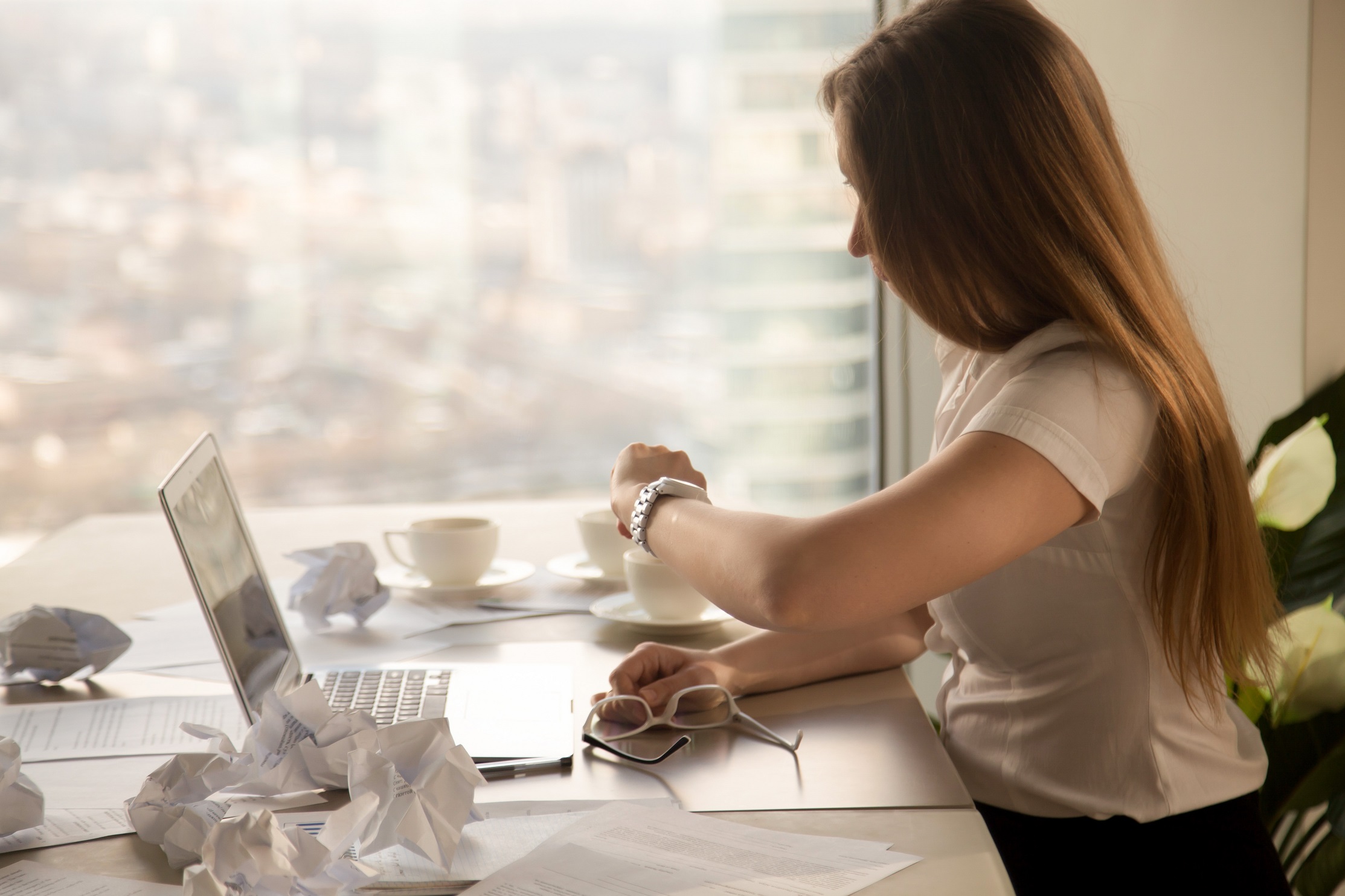 Overworked businesswoman looking at wristwatch, checking time to Woman looking at her watch in office.