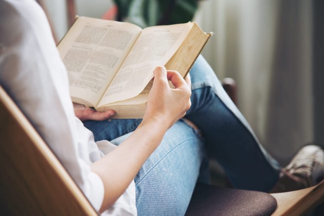 Photo of woman reading book illustrates blog: "5 New Year's Resolution Ideas for 2023"