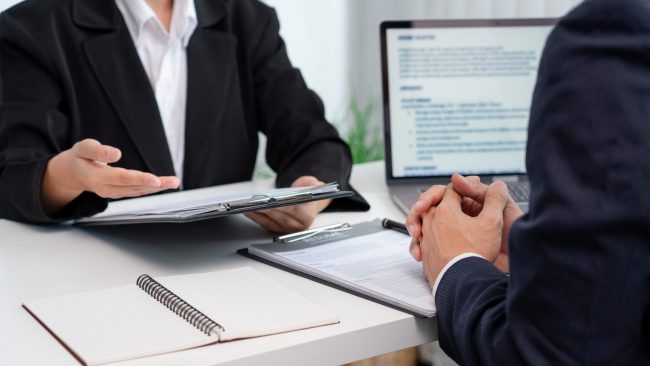 Photo of two businessmen talking at a desk