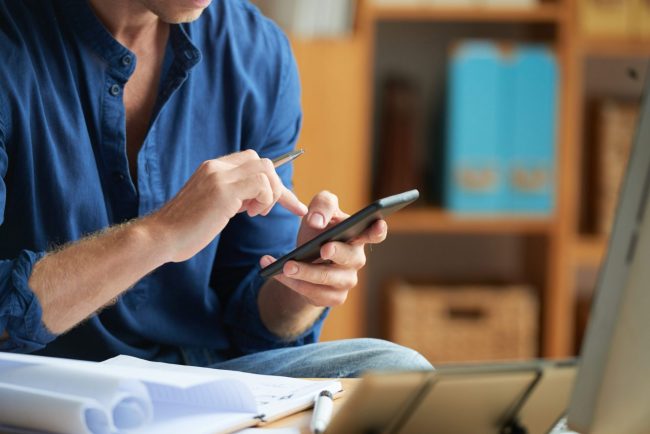 Photo of man writing on a smartphone illustrates blog: "4 Easy Ways To Improve Your Written Communication"