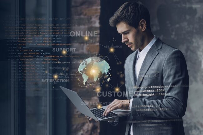 business-ai-fp Man in business attire holding laptop with hologram Earth globe floating in front of him illustrates blog "How Can Small Businesses Use AI?"