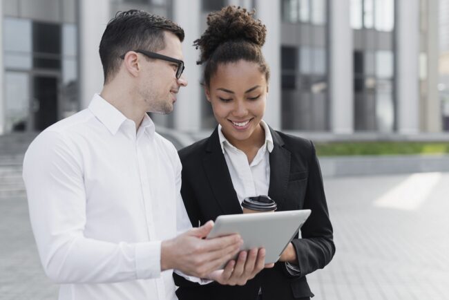 businessman-businesswoman-tablet-fp Businessman and businesswoman looking at tablet illustrate blog "What Is an EIN Number? Does My Business Need One?"