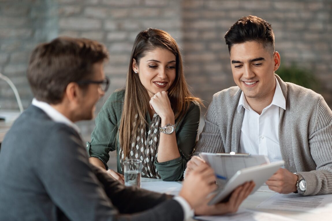 Man in business attire showing tablet to couple illustrates blog "How To Research Your Financial Options as an Entrepreneur"