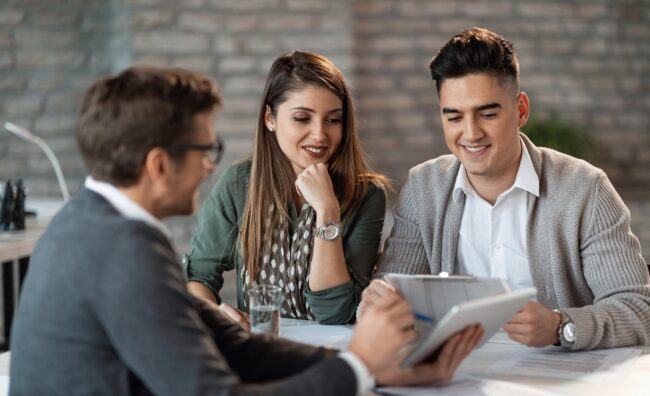 Man in business attire showing tablet to couple illustrates blog "How To Research Your Financial Options as an Entrepreneur"
