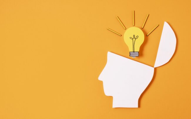 idea-business-fp Paper cutout of a man's head whose top is open like lid with a lightbulb coming out of it.