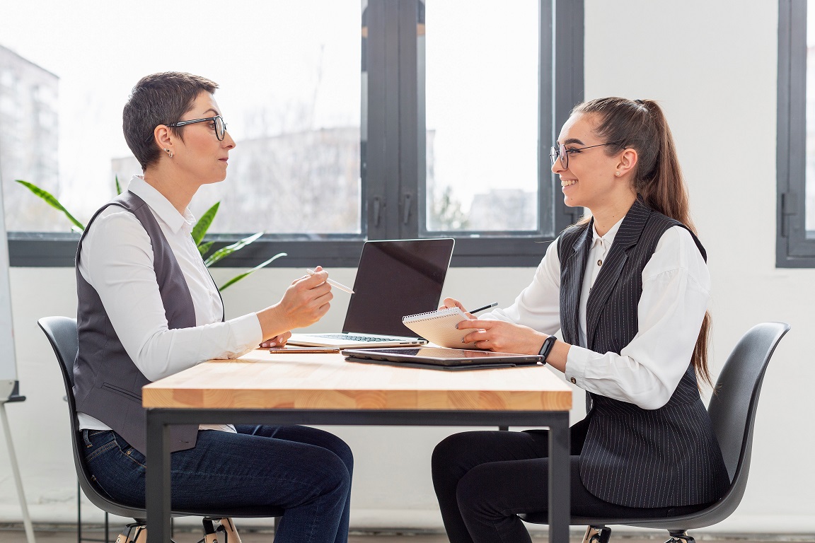 job-interview2-FP Two women in business attired sitting at a desk illustrate blog "Recruiting Tips for Small Businesses: How To Find the Right Candidates"