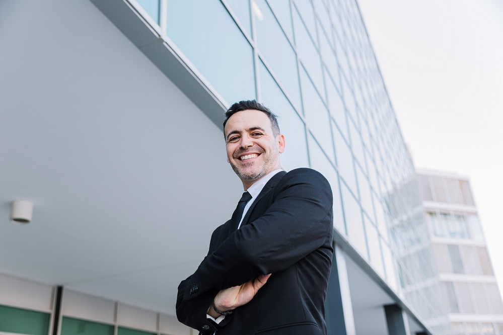 leadership-FP Man with crossed arms posing in front of building.